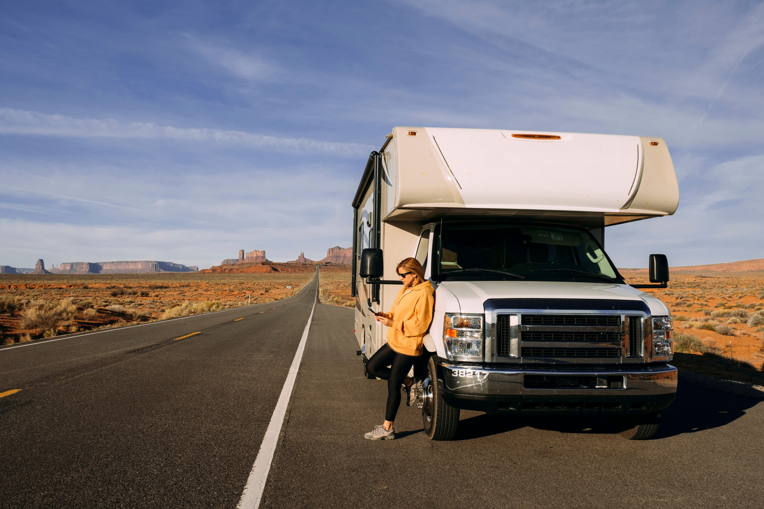 A woman travels by motorhome through Monument Valley in the USA desert and checks her mobile phone parked on the side of the road | I Heart RVing RV tech